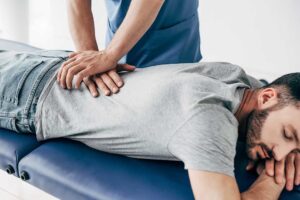 A chiropractor gently adjusting a patient's lower back in a professional clinic setting.